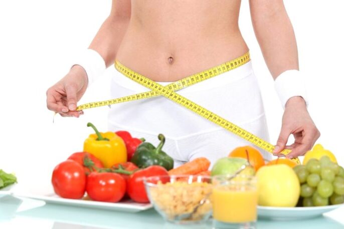 girl measuring her waist on groceries background
